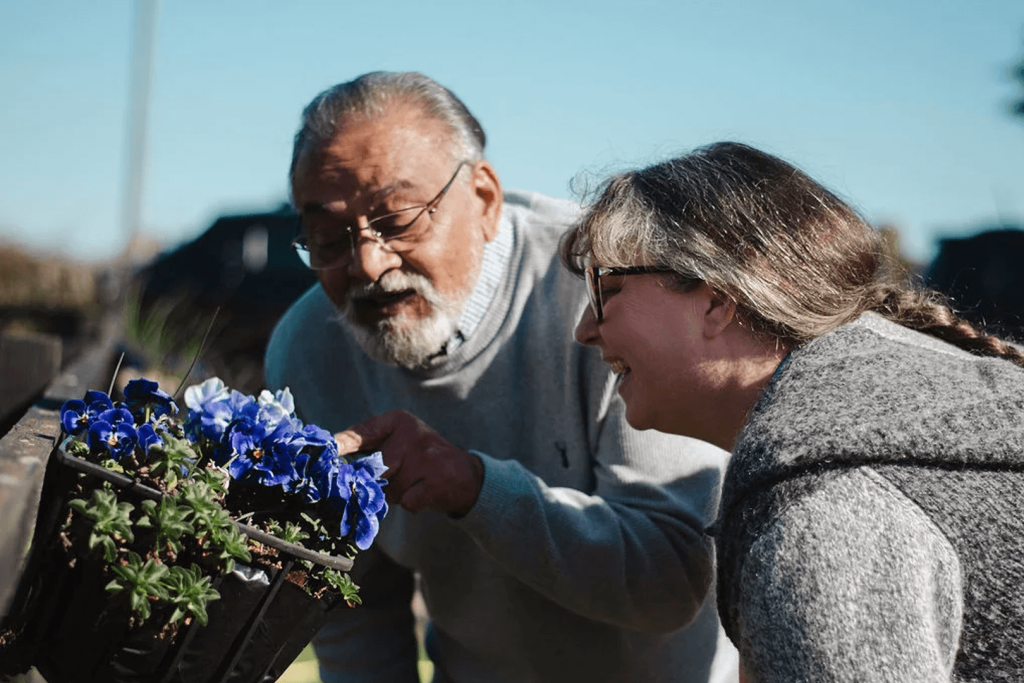 Older adult and caregiver enjoying gardening together outdoors