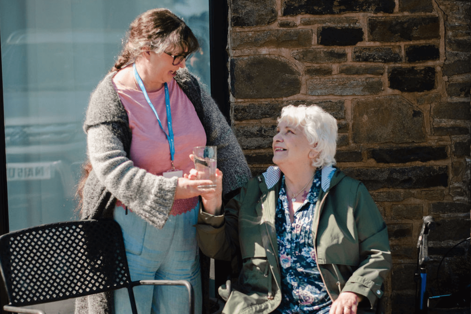 middle aged carer giving water to the elderly client
