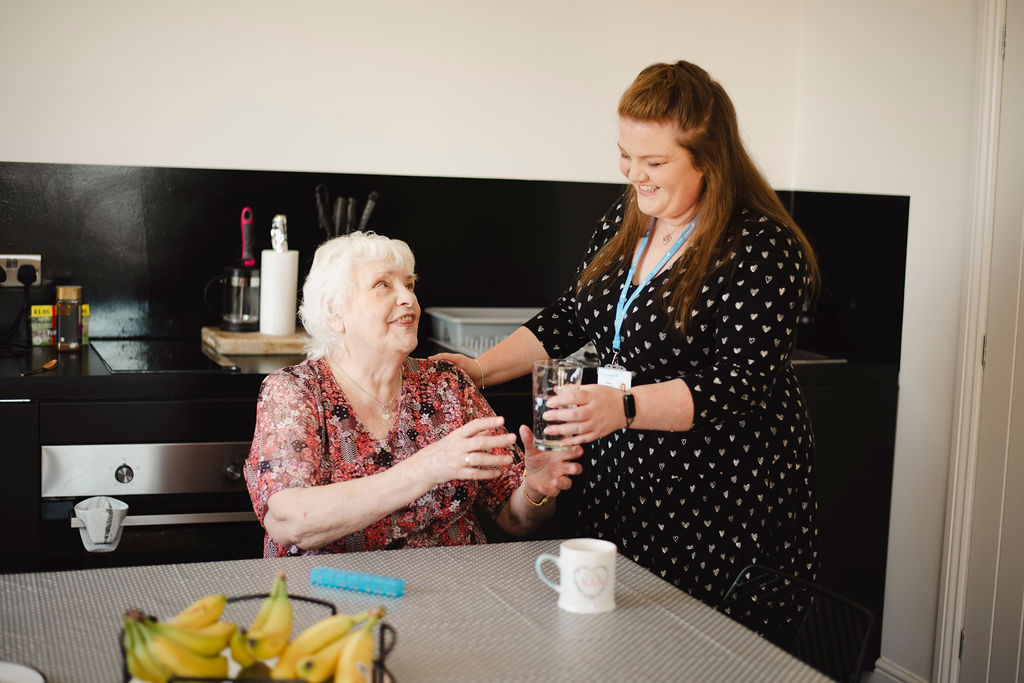 Carer supporting an elderly woman at home in Windsor
