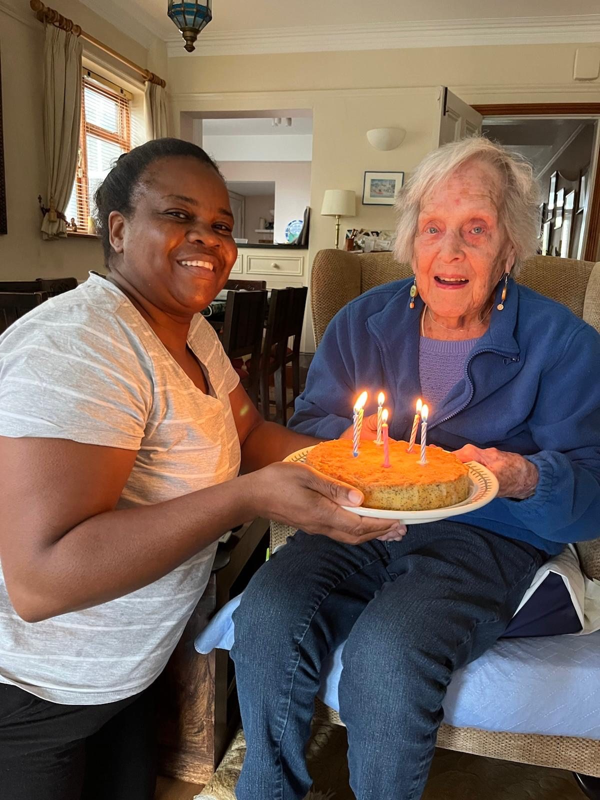 Photo of a carer offering a birthday cake to a client