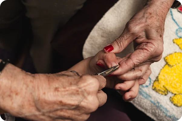 Caregiver gently trimming an older person's fingernails with nail clippers