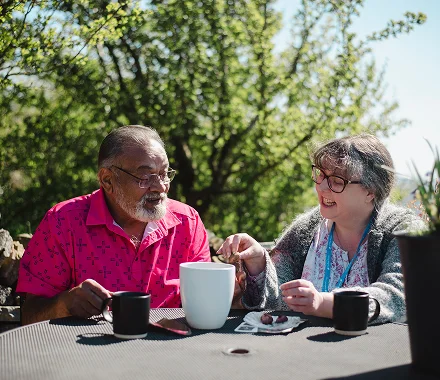 A Visiting Angels carer providing Companionship Care to an older woman on a sunny patio in Northwood, Middlesex — friendly, attentive, CQC registered