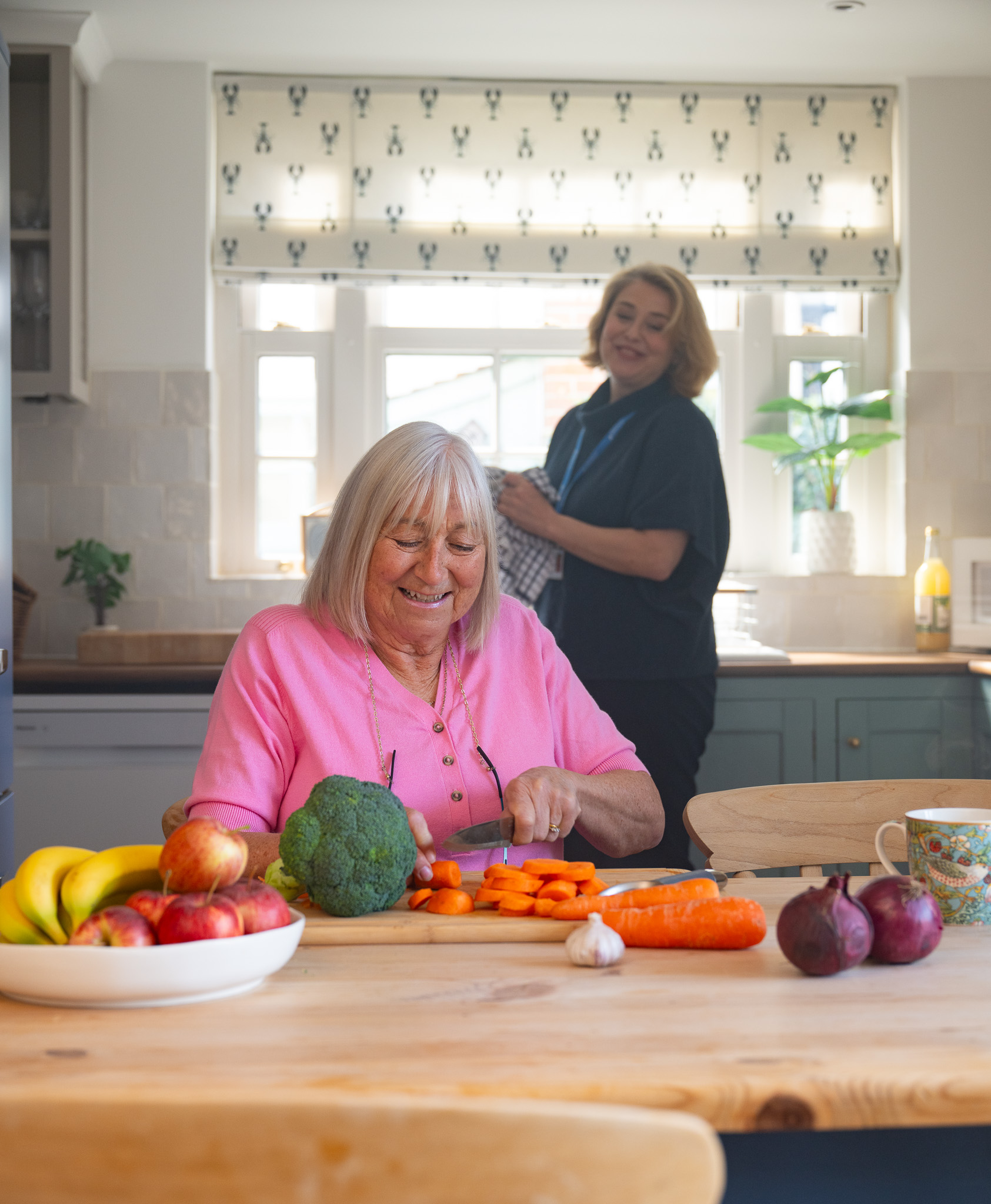 caregiver with elderly client preparing fresh vegetables