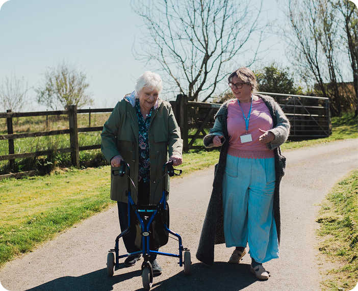 carer pushing elderly man in wheelchair outside