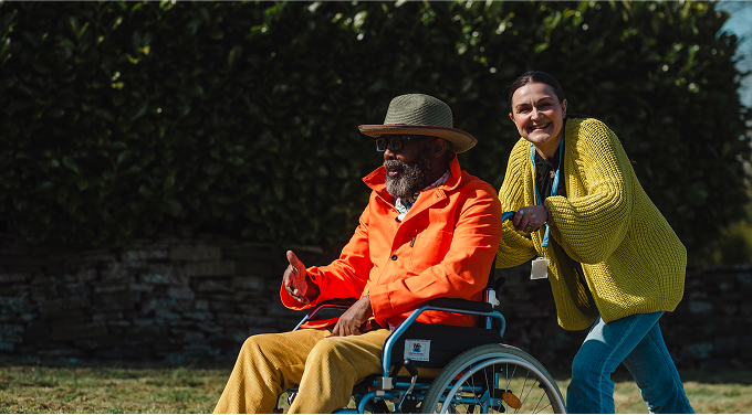 carer pushing elderly man in wheelchair