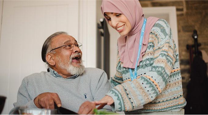 carer helping elderly man to cut vegetables at home