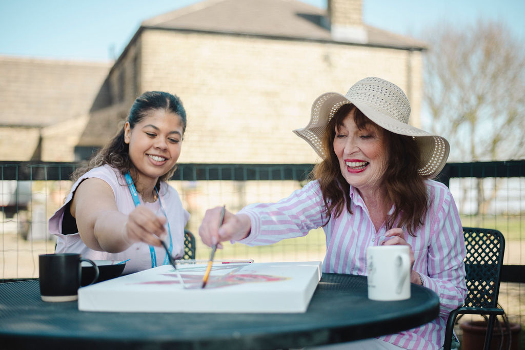 A Visiting Angels carer providing companionship care to an elderly woman at home in Woodstock, Oxfordshire — compassionate, professional, CQC rated home care