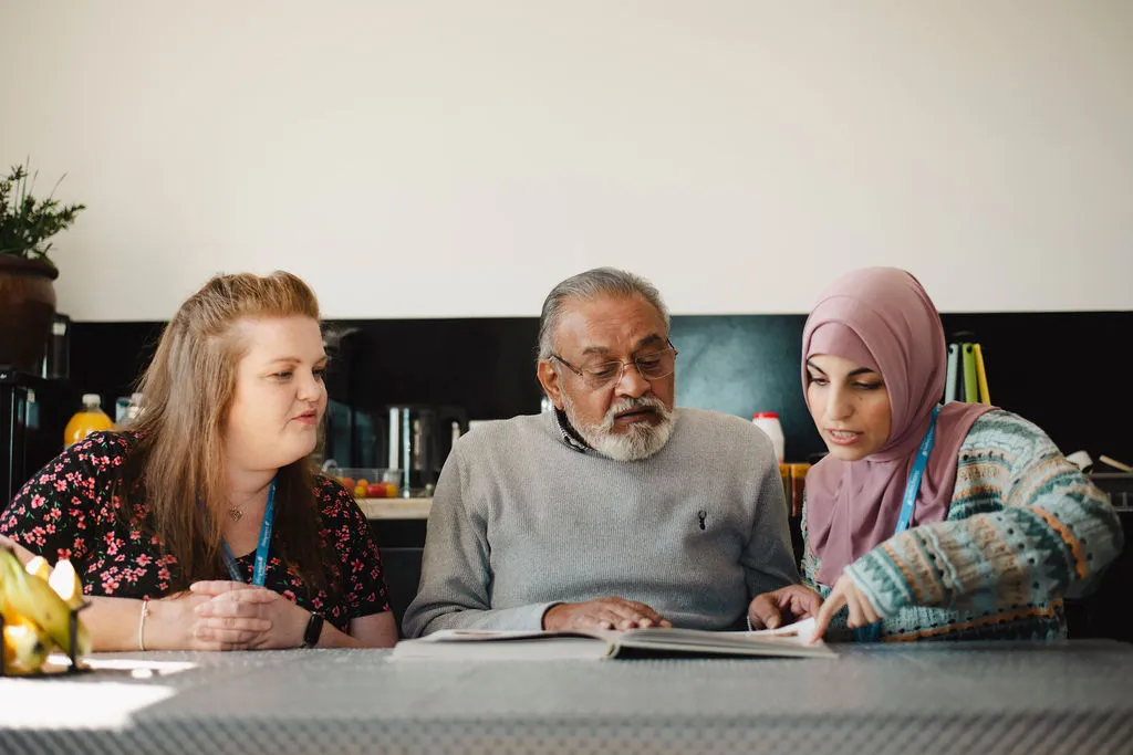 A Visiting Angels carer reviewing Covid‑19 Home Care Oxford safety guidance with elderly clients at home in Oxford, Oxfordshire — compassionate, professional, CQC rated support