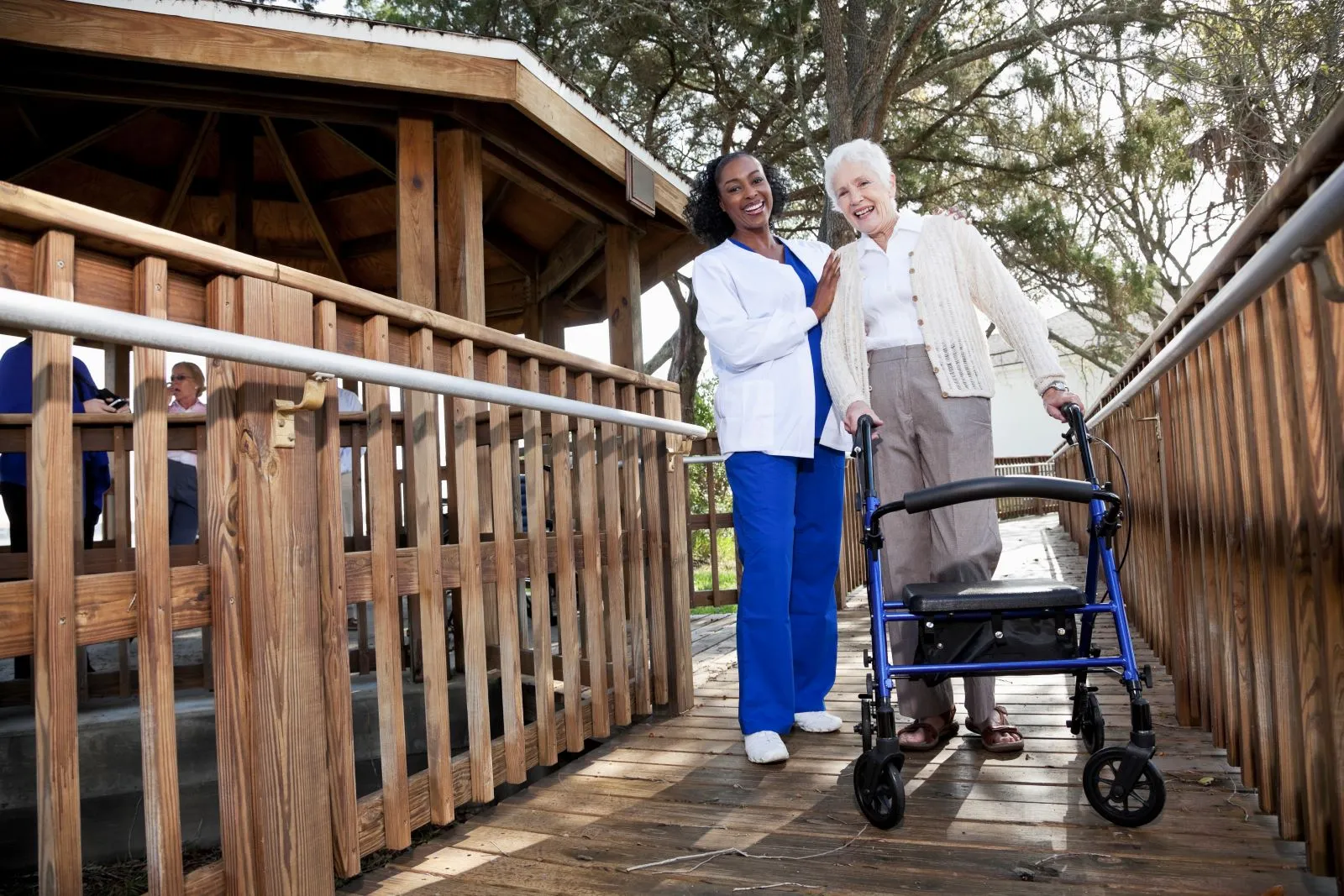 A Visiting Angels carer providing companionship and mobility support to an elderly woman outdoors in Oxford, Oxfordshire — compassionate, professional, CQC rated home care