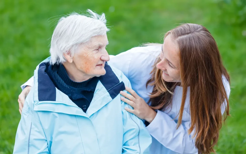 A Visiting Angels carer providing hydration support and personal care to an elderly woman outdoors in Oxford, Oxfordshire — compassionate, professional, CQC rated home care