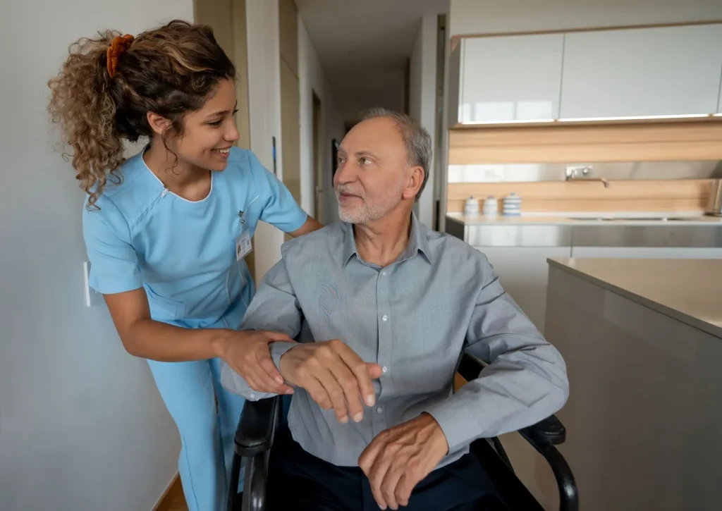 A Visiting Angels carer providing holiday respite care services to an elderly man in a wheelchair in Oxford, Oxfordshire — compassionate, professional, CQC Good rated home care