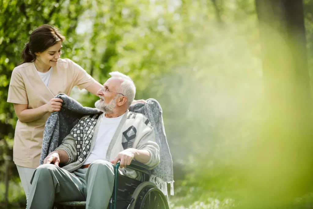 A Visiting Angels carer providing home care services to an elderly man in a wheelchair outdoors in Headington, Oxfordshire — compassionate, professional, CQC Good rated home care