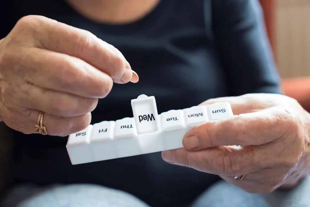 A Visiting Angels carer providing medication prompting to an elderly woman at home in Oxford, Oxfordshire — compassionate, professional, CQC rated home care