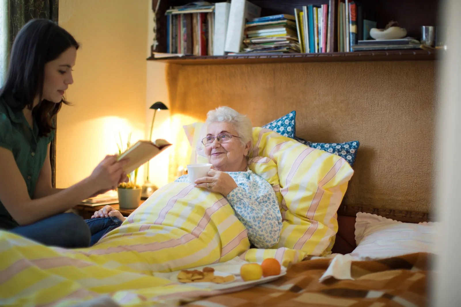 A Visiting Angels carer providing personal care services to an elderly woman in bed at home in Headington, Oxfordshire — compassionate, professional, CQC Good rated home care