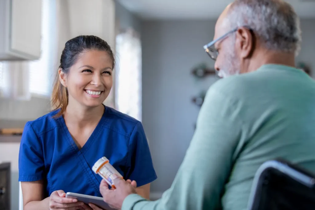 A Visiting Angels carer providing medication prompting and healthcare support to an elderly man in Witney, Oxfordshire — compassionate, professional, CQC rated home care