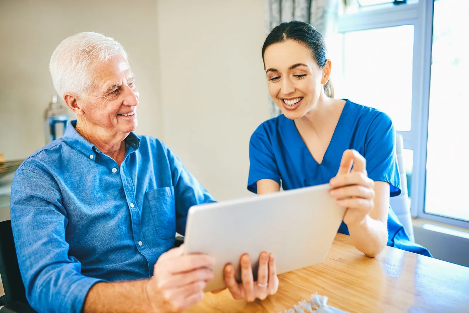 A Visiting Angels carer providing digital companionship and home care to an elderly man at home in Kidlington, Oxfordshire — compassionate, professional, CQC rated home care