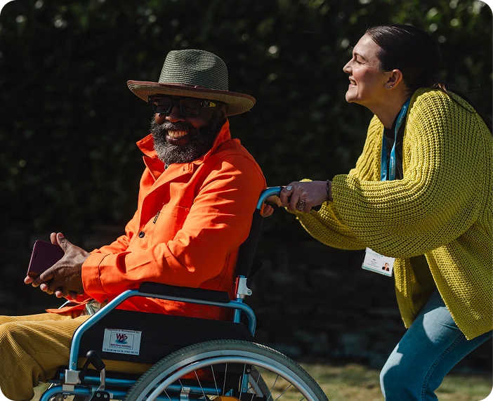 A Visiting Angels carer providing mobility and companionship care to an elderly man in a wheelchair in Headington, Oxfordshire — compassionate, professional, CQC rated home care