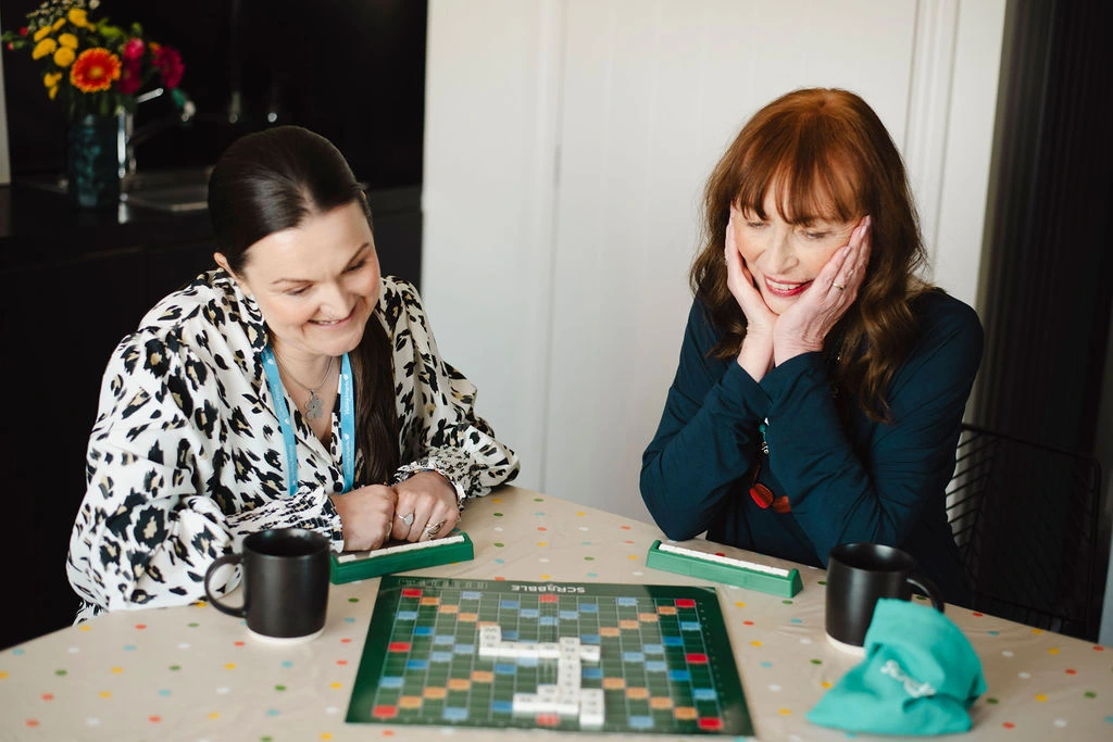 Visiting Angels Oxford home carer enjoying a game of Scrabble with elderly client in the comfort of home.